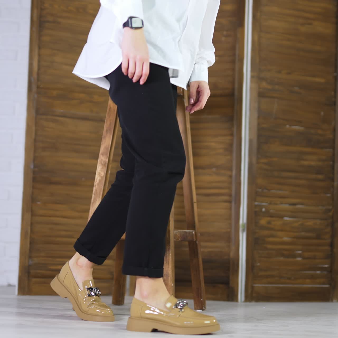 Blonde long-haired lady squatted to touch up her fashionable shoes. Model smiles and stands up to walk away in beige plain loafers