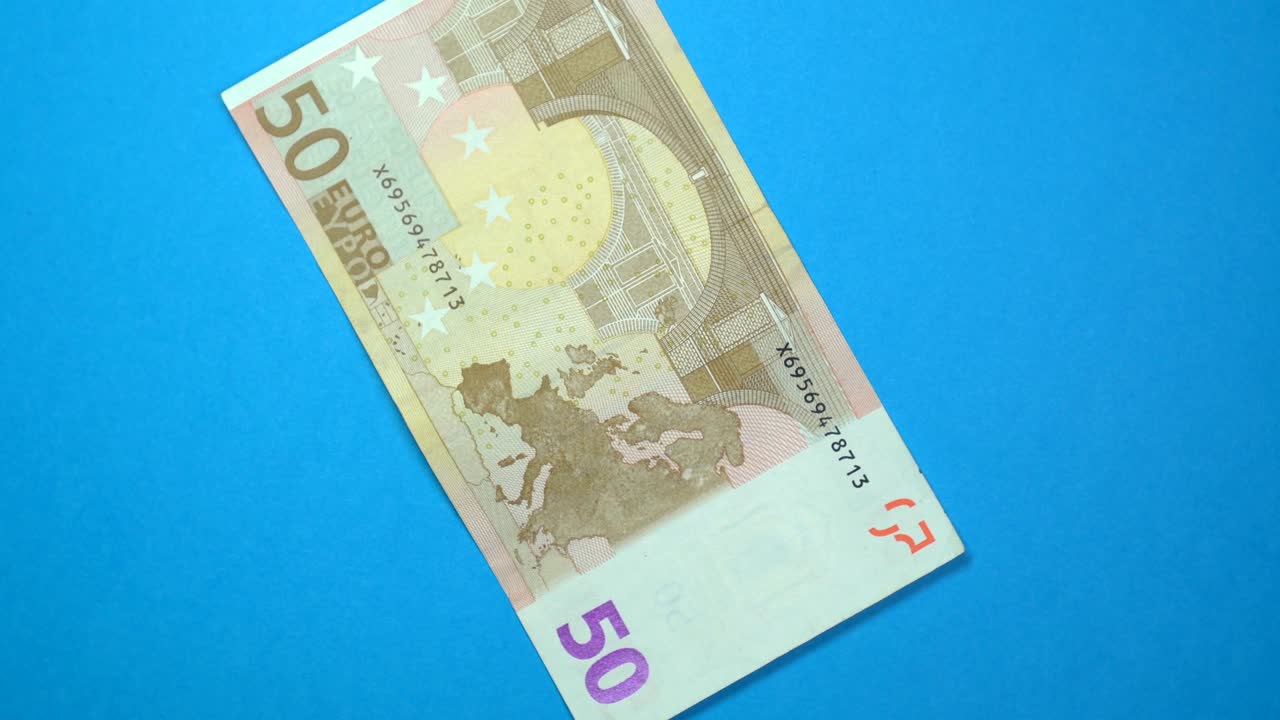 50 euro slowly spinning on a rotating blue background.