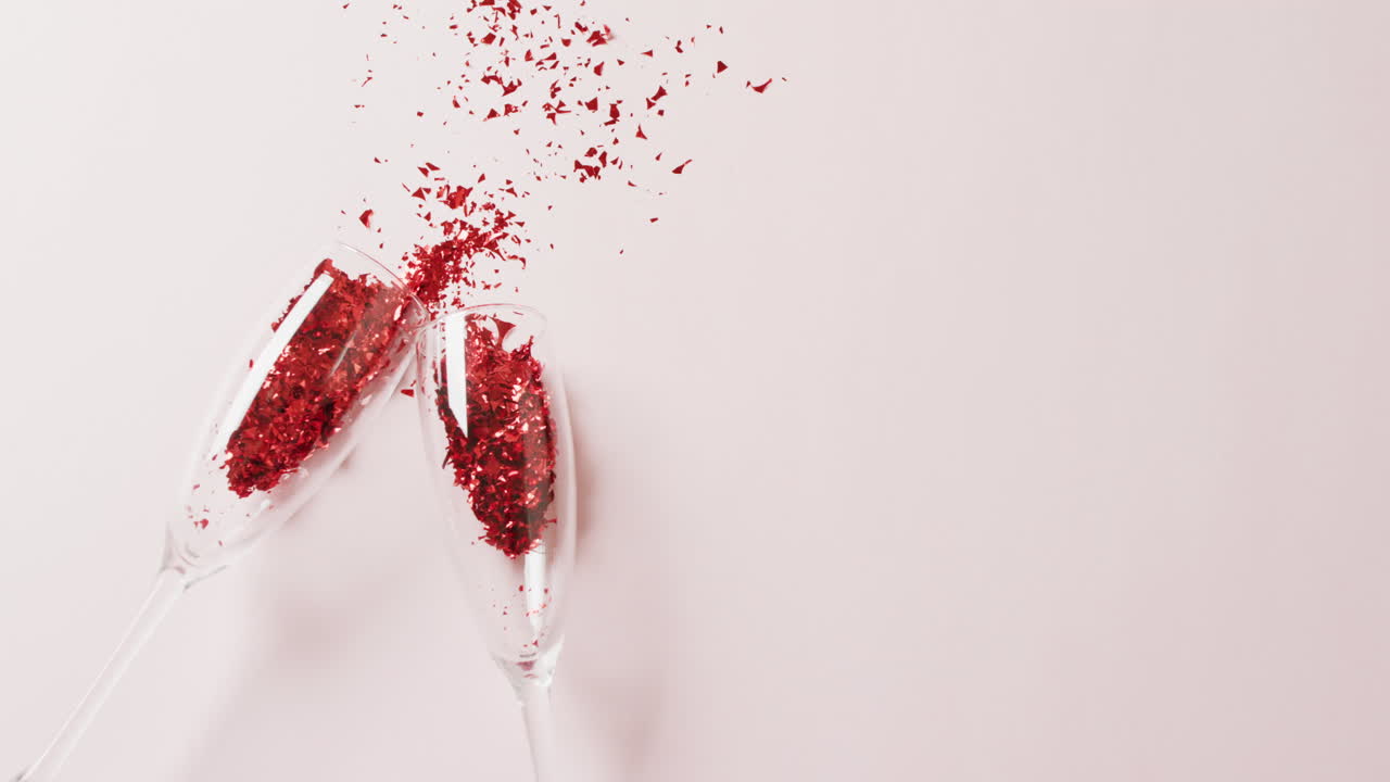 두 개의  ⁇ 페인 컵이  ⁇ 은 반 ⁇ 이는 콘페티를 흘리는 비디오,  ⁇  배경에 복사 공간이 있습니다.