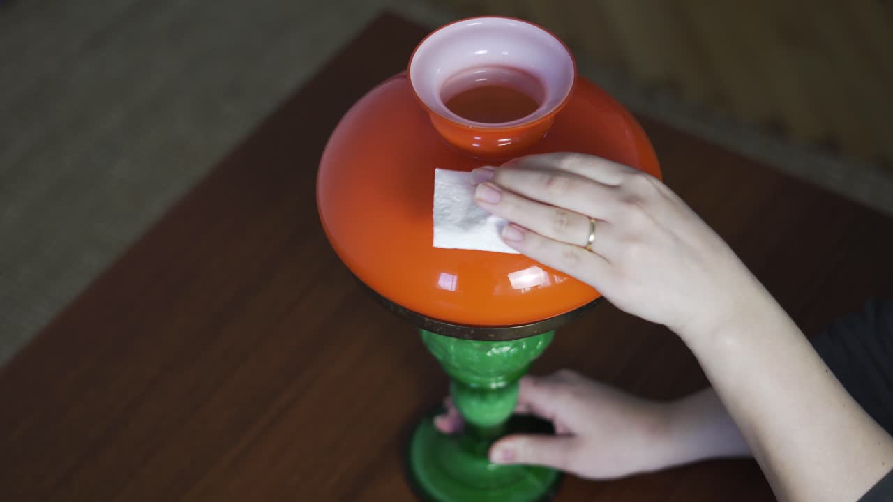 Primer plano de mujeres limpiando una lámpara vintage antes de la venta, útil para contenido de antigüedades, reventa, mercadillo y restauración del hogar