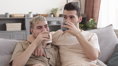two young men drinking tea and talking at home