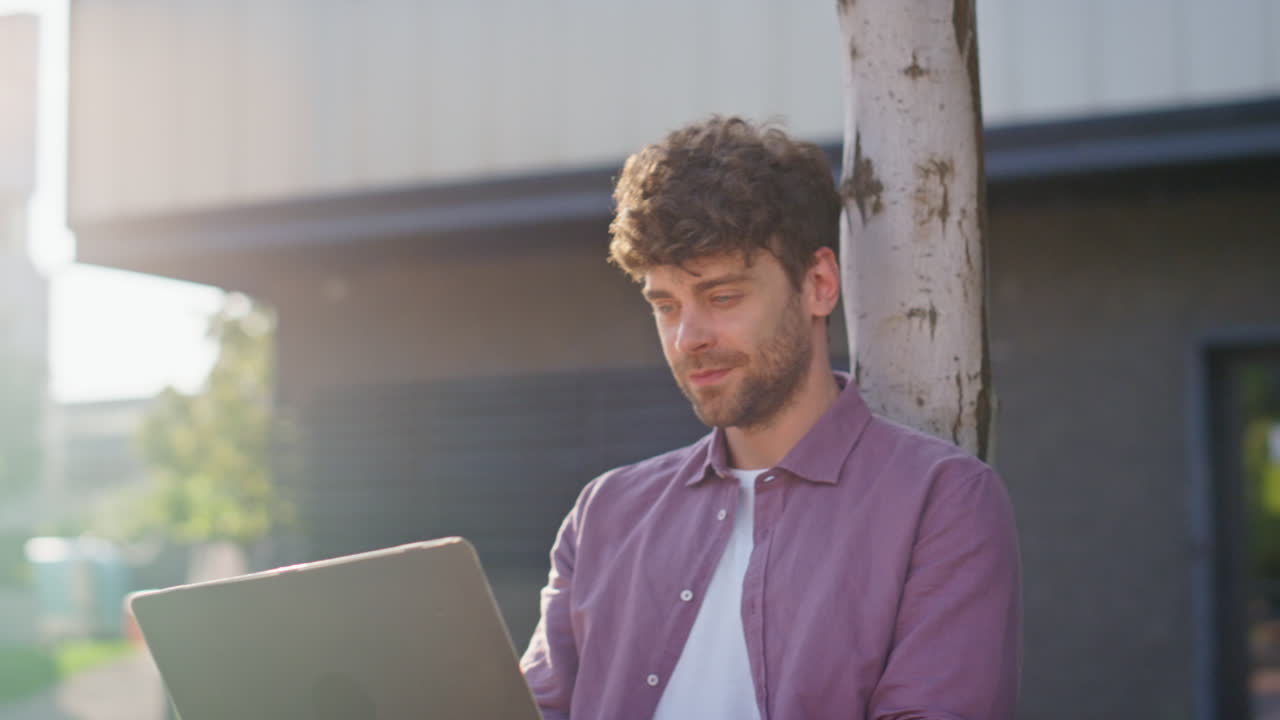 freelancer al aire libre llamando a la computadora portátil en línea en la calle. tipo sonriente agitando la mano