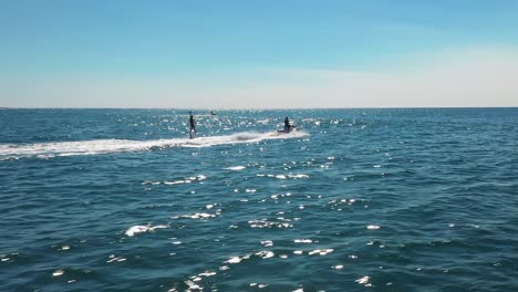 jet ski's towing athletes hydro foiling on the ocean aerial view on bright summer's day in sydney, australia