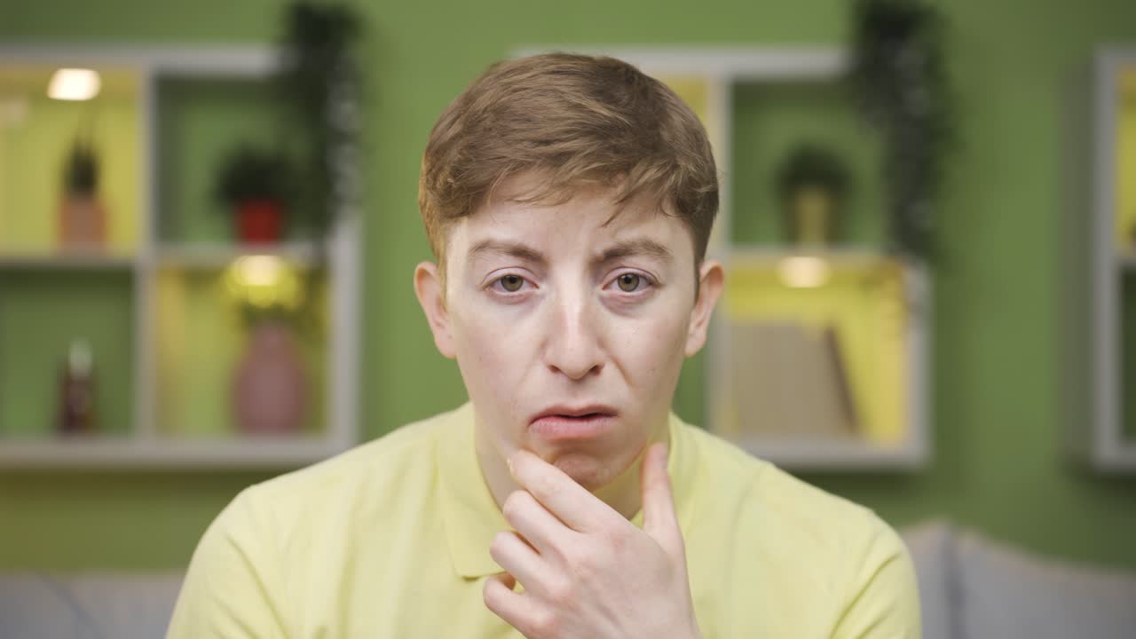 un joven de primer plano se muerde las uñas mientras mira a la cámara.