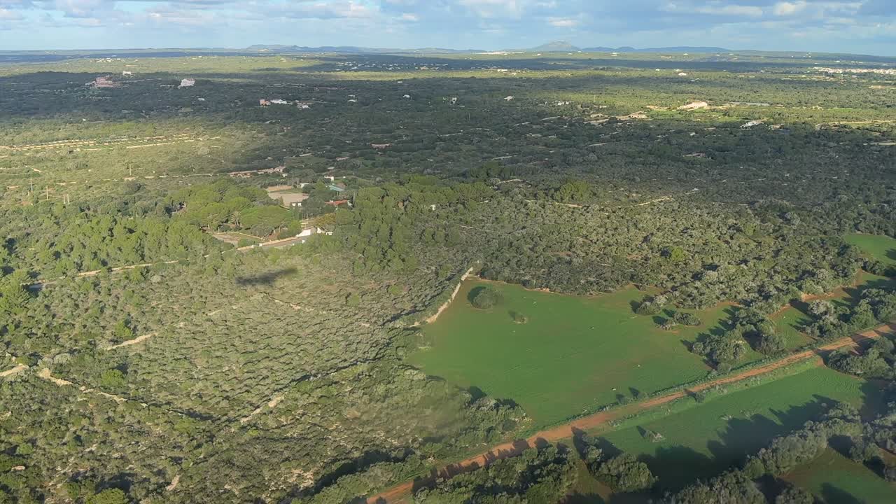 Vista aerea laterale sinistra dell'ombra di un aereo a reazione sul terreno in un paesaggio rurale a Minorca, Spagna