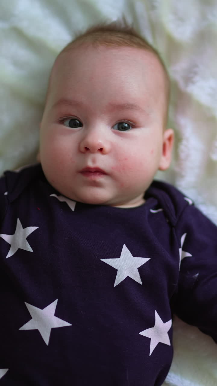 Cute small newborn boy. Gorgeous little baby lies on the bed. Vertical video