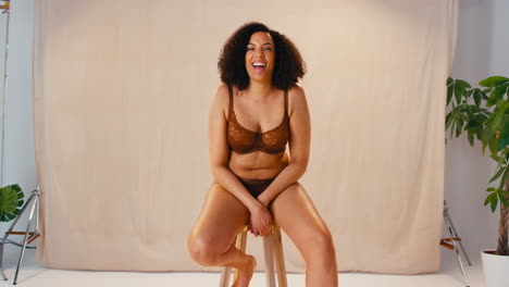 retrato de estudio de una mujer natural sonriente y segura en ropa interior que promueve la positividad corporal