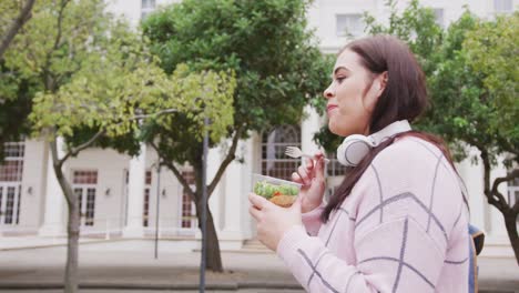 Young-Caucasian-woman-eating-and-walking