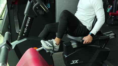 Asian man in sportswear cycling on recumbent bike in bright, modern gym with fitness equipment