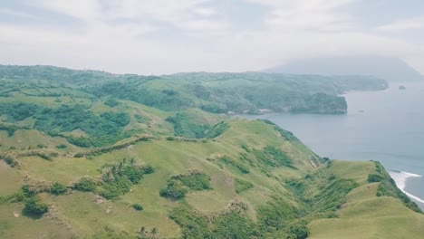 Cinematic-aerial-drone-view-of-a-picturesque-landscape-of-ocean-meeting-mountains-in-Batanes,-Philippines