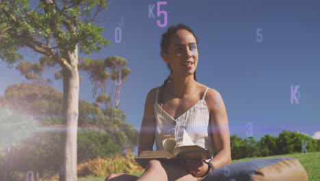 Animation-of-letters-and-numbers-over-smiling-biracial-woman-reading-in-park