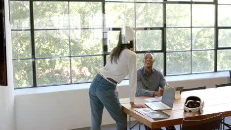 laughing and discussing work, colleagues using laptop and documents in office