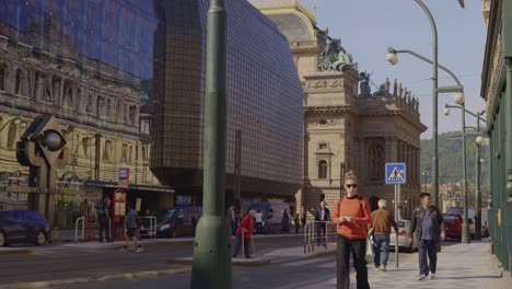 busy street bustle on prague's national avenue near the theatre on a sunny day. pedestrians, trams and cars.