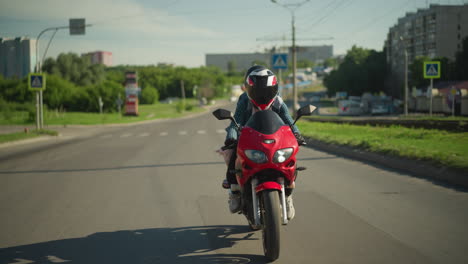 two sisters ride on a red power bike as they travel on an urban road, the background features a blur view of cars, buildings, and electric poles, with a blur view of a car coming out from bend