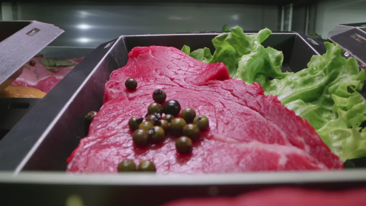 Close-up view of raw smoked meats and herbs arranged and displayed in a professional kitchen vending machine.