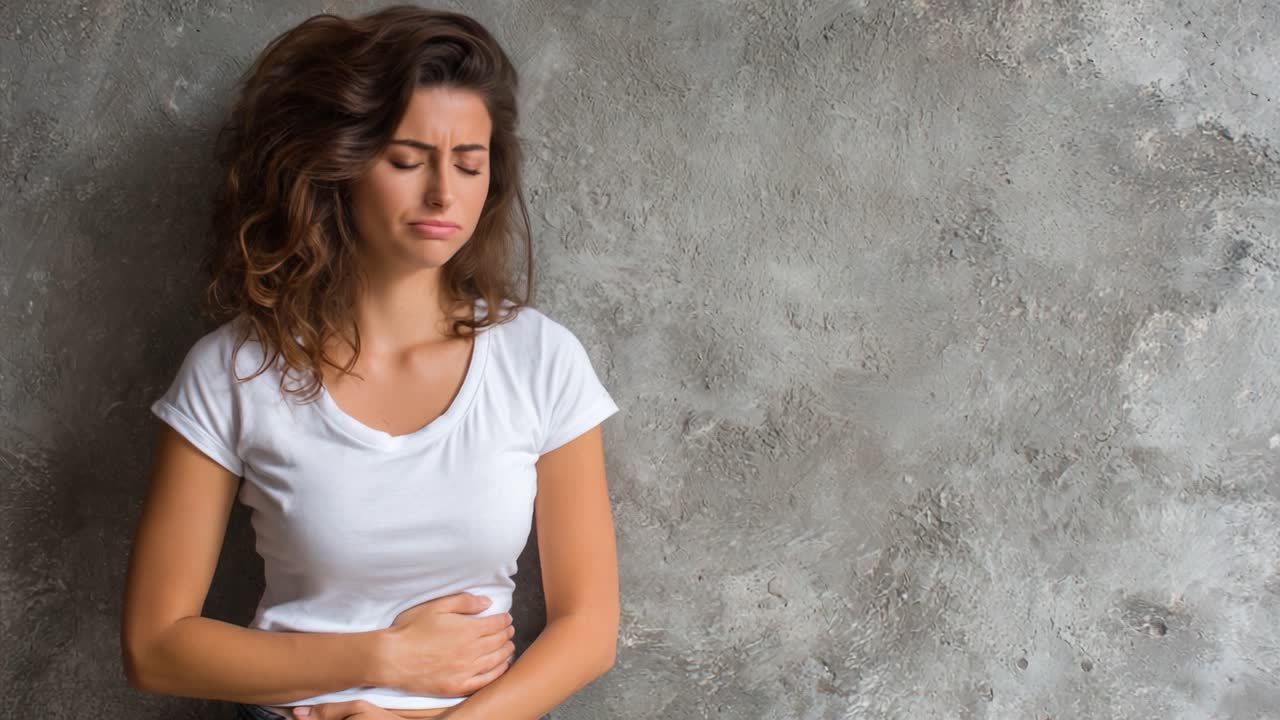 A Young Woman Expressing Discomfort Against a Textured Gray Wall: A Visual Representation of Emotional and Physical Struggles