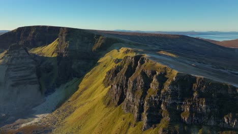 Huge-ancient-landslip-ridges-in-early-morning-winter-sunshine-with-reveal-of-wider-mountainous-and-moorland-landscape-beyond