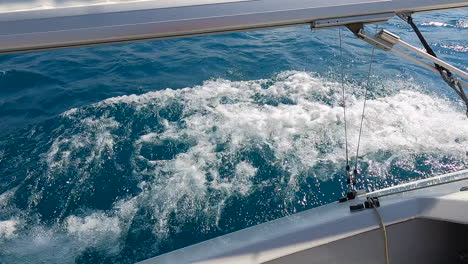 Watching-the-water-moving-on-the-starboard-side-of-a-sailboat-as-it-sails-at-sea,-no-people