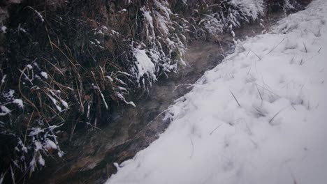 Winter-scenery-trickling-brook-surrounded-by-snowy-banks