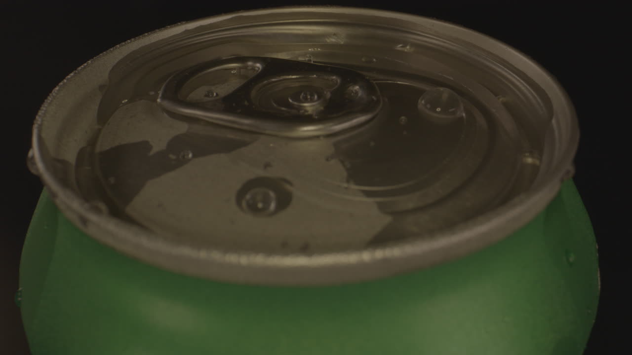 회전하는 소다 캔 위에 있는 물방울을 닫습니다.