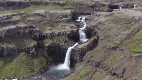 Multi-layered-waterfall-in-rocky-valley-in-Iceland,-Berufjörður,-aerial