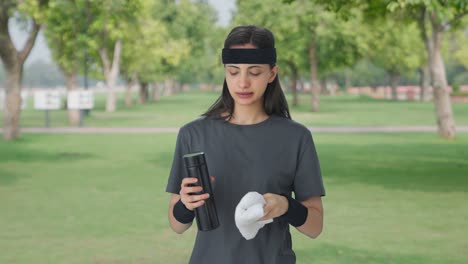 indian girl wiping sweat and drinking water after workout