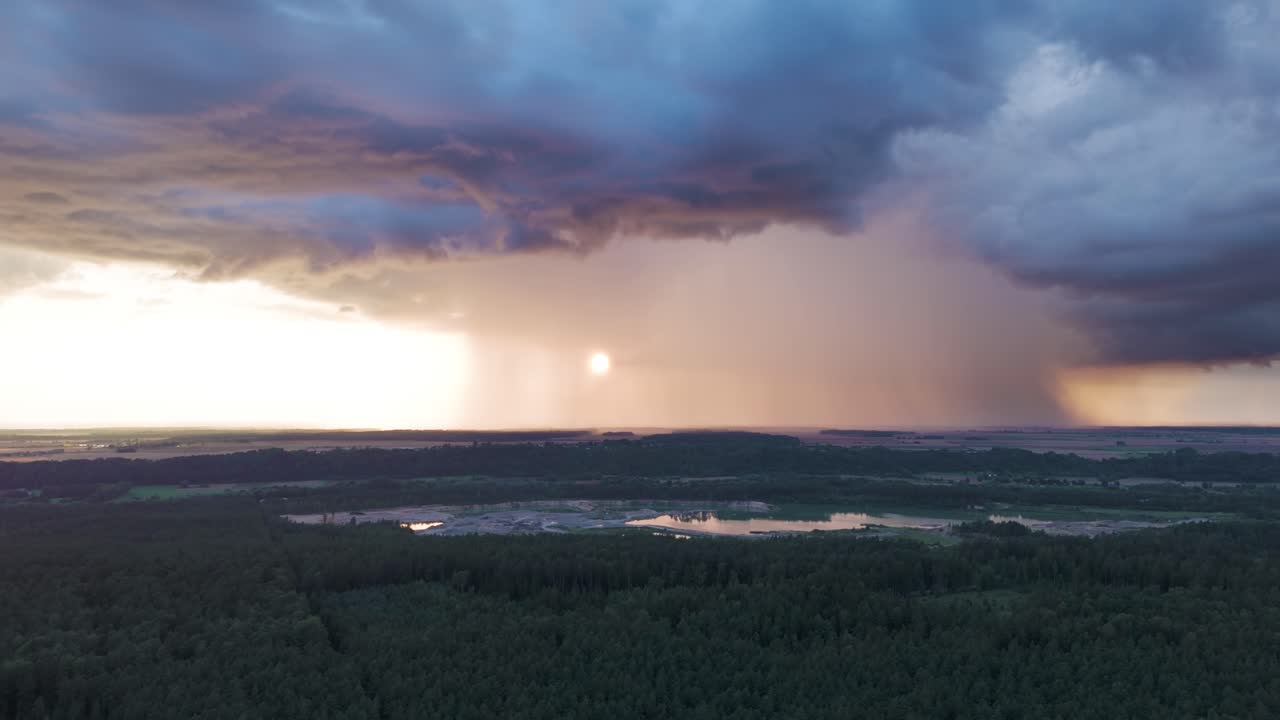 Powerful dark storm clouds and rainfall with sunshine behind, aerial view