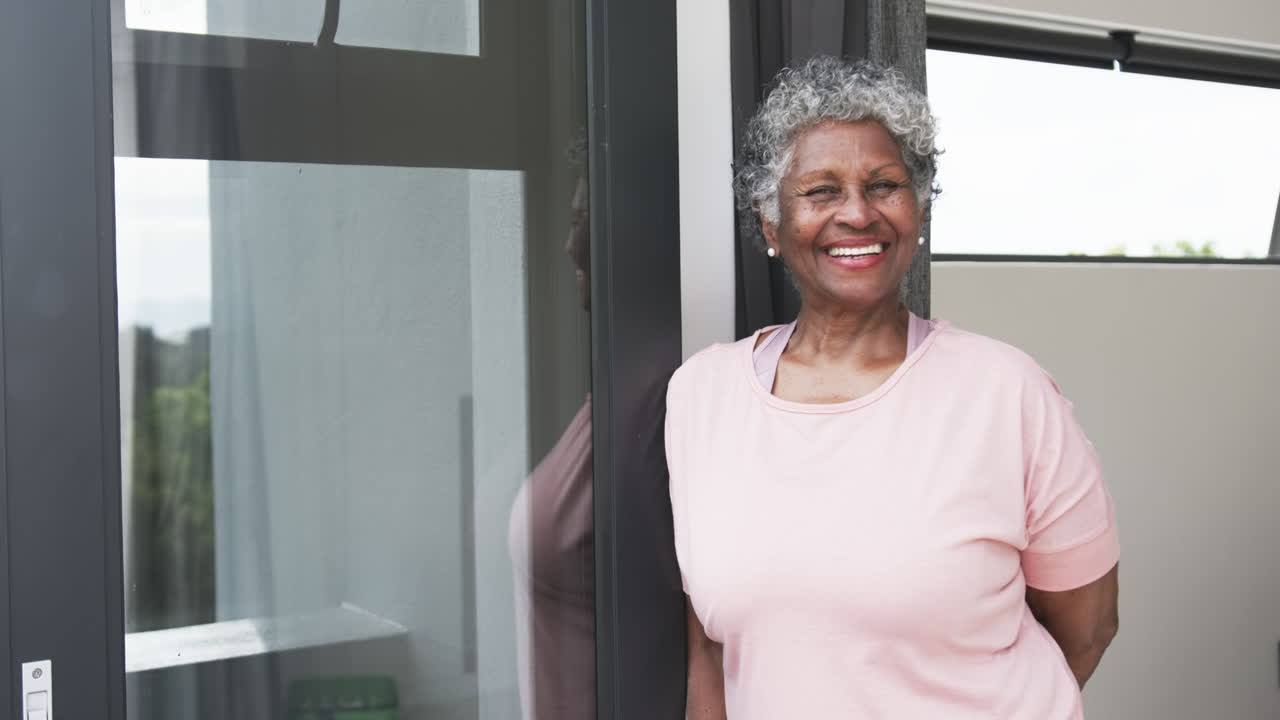 retrato de una mujer afroamericana feliz y anciana sonriendo junto a la ventana, espacio de copia, cámara lenta