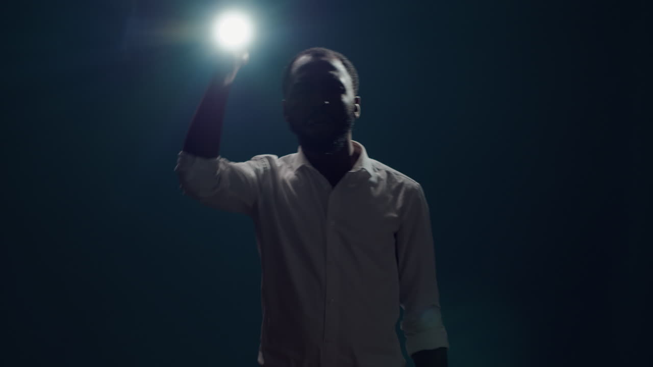 A man holds up a flashlight in the dark
