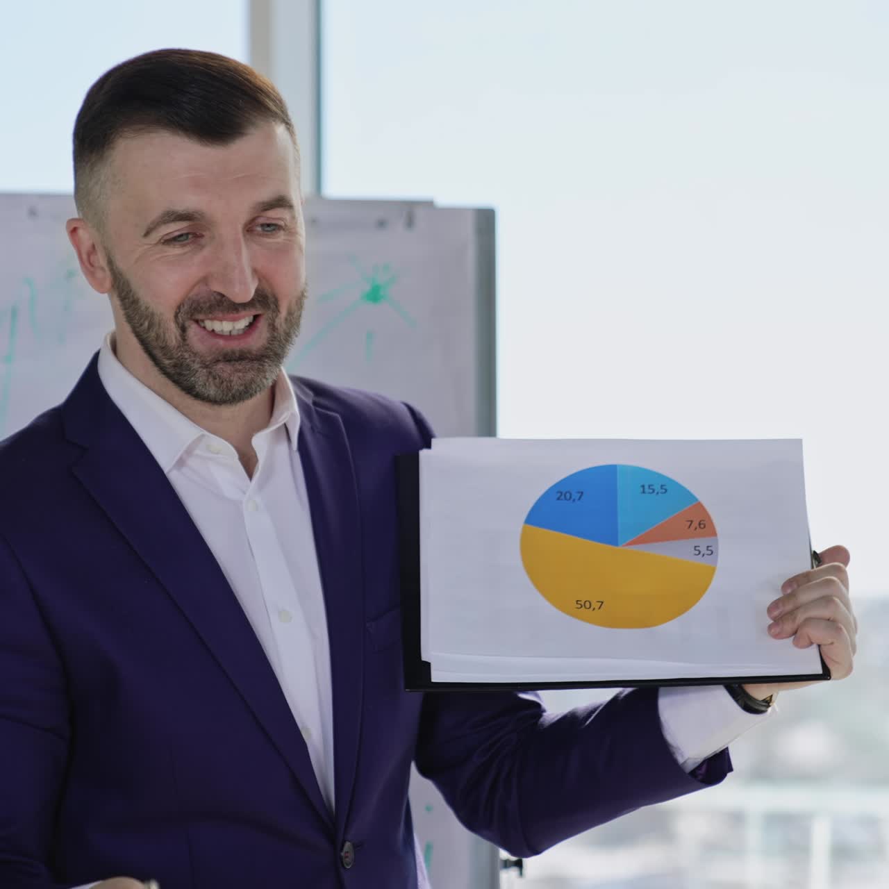 Speaking leader shows the graph and waves hand with pen actively. Boss explaining chart to his employees. Light blurred backdrop