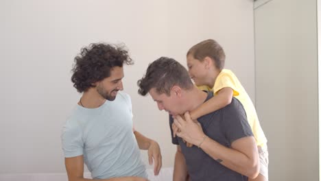 niño alegre y sus dos papás disfrutando de la actividad doméstica