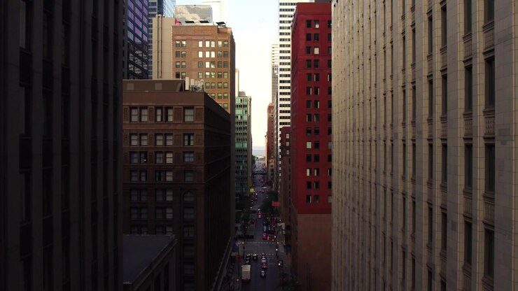 Ripresa aerea con drone che guarda in basso un corridoio stradale del centro di Chicago, incorniciato da alti edifici per uffici, traffico e densa architettura urbana