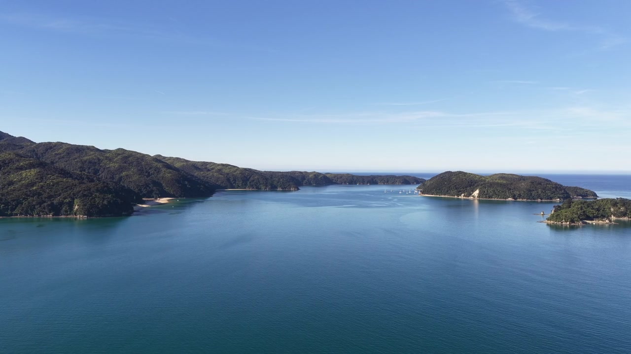 Luftpanorama af et roligt fjordlandskab på New Zealands Sydø med blåt vand, skovklædte bakker og fjerntliggende øer, ideel til koncepter om rejser, natur og fredfyldt flugt.