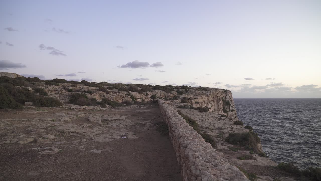 caminando en plateu hacia una colina rocosa cerca del mar mediterráneo en malta en una tarde soleada de color púrpura
