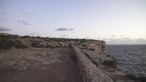 walking on plateu towards rocky hill near mediterranean sea in malta on purple colour sunny evening