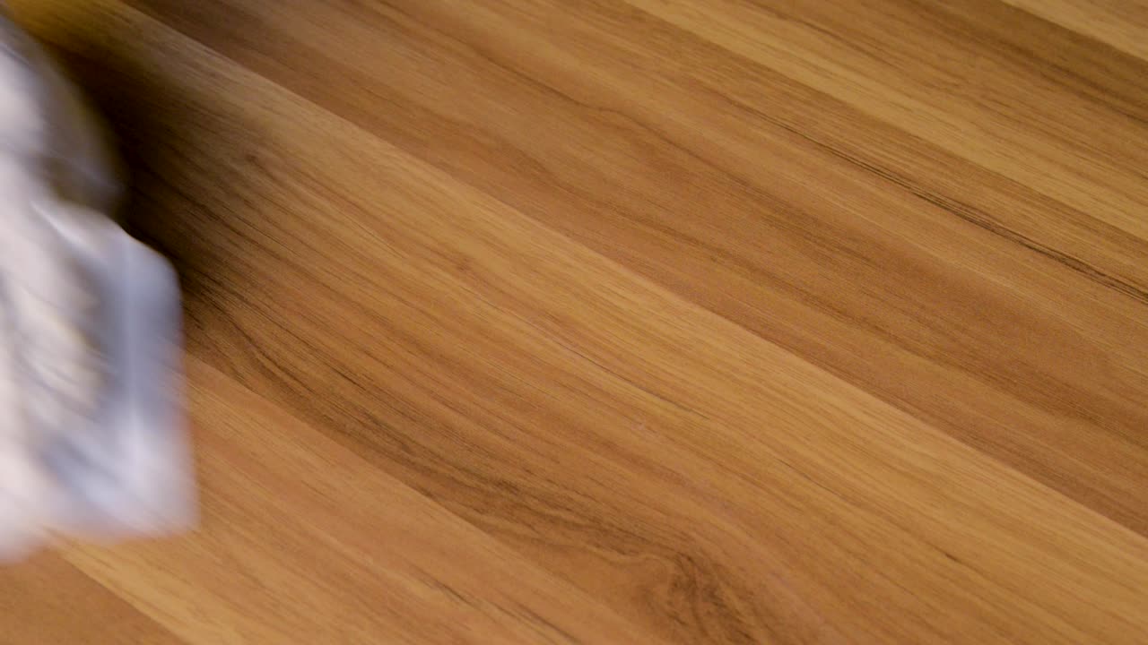 persona con guantes protectores limpiando el polvo con un spray y un plumero mientras limpia en la mesa