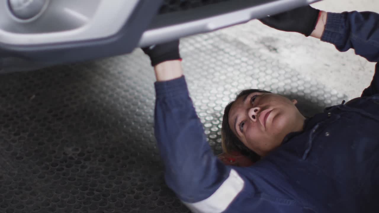 자동차 서비스 스테이션에서 자동차  ⁇ 에 누워서 일하는 여성 메카닉