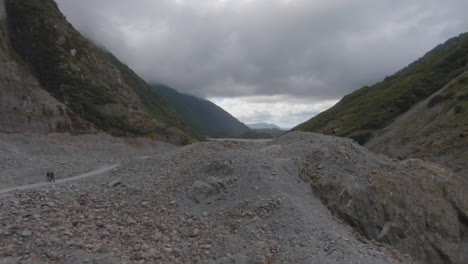 overview on a rubble landscape with a river on a very cloudy day, franz-josef glacier, new zealand