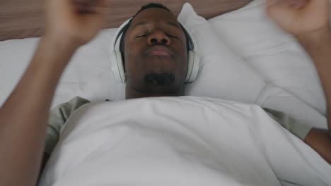 man listening to music and dancing in bed