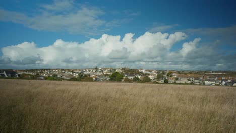 4K-Cinematic-landscape-shot-of-giant-clouds-hovering-over-a-small-island-town,-on-Portland,-Dorset,-in-England,-on-a-sunny-day