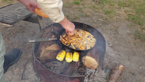 A man cooks fish and chips on a campfire in Australia