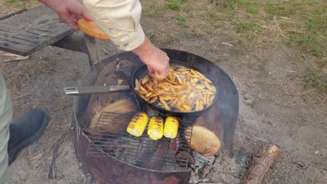 a man cooks fish and chips on a campfire in australia