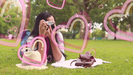 woman taking photos in park with pink heart animation overlay