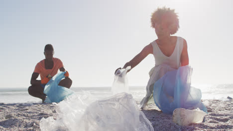 una pareja afroamericana segregando residuos juntos en una playa sucia y soleada