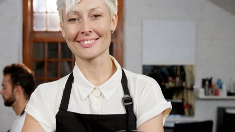peluquera de pie con el brazo cruzado en un salón