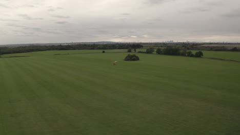 seguimiento lateral del girocóptero desde el dron mientras se lanza con el horizonte de londres en una toma