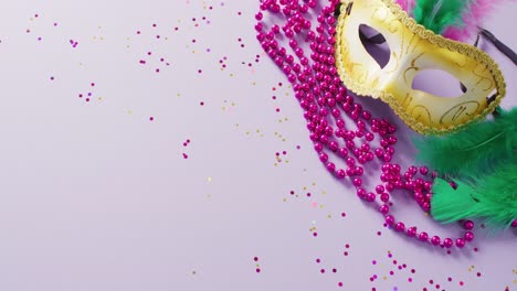 video of carnival masquerade mask with green feathers and pink mardi gras beads, with copy space