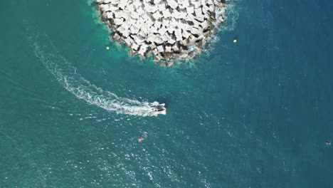 el barco sale del puerto, el puerto redondea la esquina de un gran rompeolas, el dron de arriba hacia abajo, vista de pájaro estática.