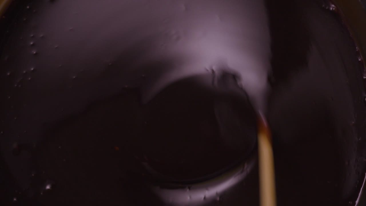 primer plano estático desde arriba de chocolate muy oscuro que se agita con un palo de madera