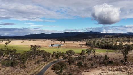 drone camera glides over a rural landscape with farm ponds, open fields, and scattered trees under partly cloudy skies in stanthorpe, queensland